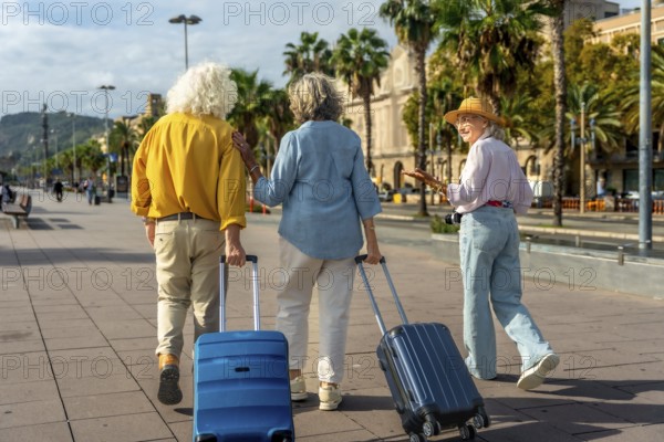 Group of senior women friends walking on a sunny urban promenade, pulling their luggage, and enjoying a relaxing travel vacation exploring a new city together