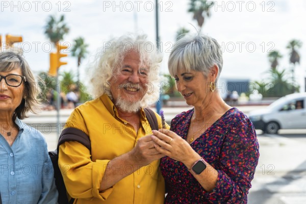 Senior couple embracing on a sunny city street, smiling and looking at a smartphone while enjoying retired life, travel and modern connection outdoors together