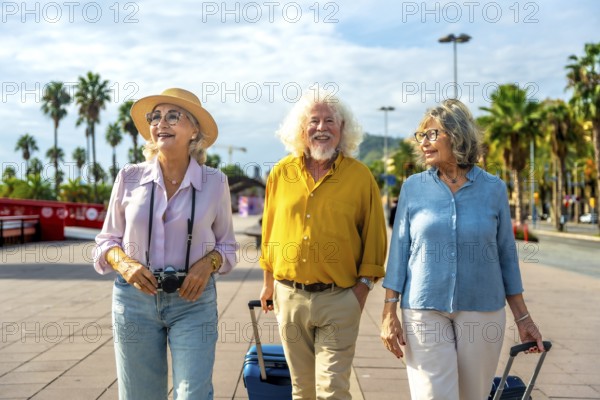 Senior men and women walking outdoors with luggage and a camera, enjoying a tropical leisure trip together with happiness and friendship under palm trees