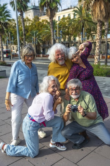 Cheerful group of senior friends traveling together, capturing fun memories with an analog camera while exploring a city street lined with palm trees on a sunny day