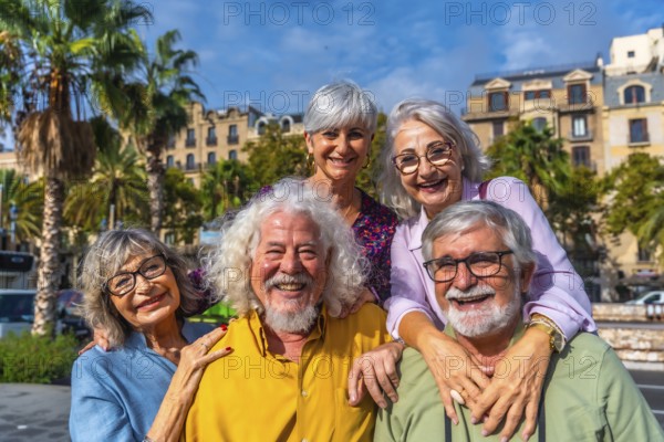 Happy multiracial senior friends smiling and embracing on a sunny city street during vacation, enjoying retirement togetherness, friendship and active, carefree leisure