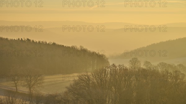 Blurred hills and golden sky at sunrise create a misty, quiet landscape, Seckmauern, Lützelbach, Maintal, Odenwald, Hesse, Germany