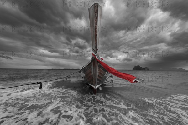 Longtail boat on the beach with dark rain clouds behind it, Koh Ngai island, Andaman Sea, Satun province, southern Thailand, Thailand