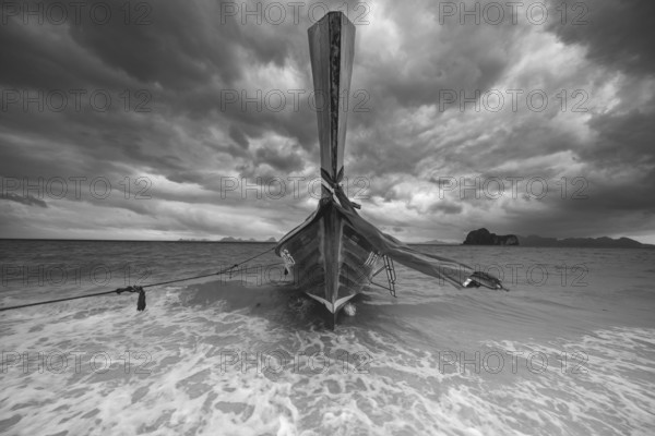 Longtail boat on the beach with dark rain clouds behind it, Koh Ngai island, Andaman Sea, Satun province, southern Thailand, Thailand