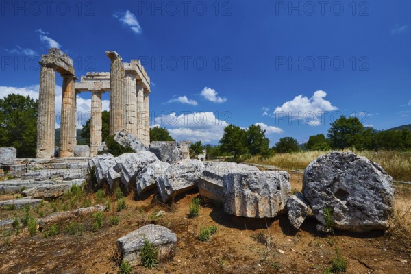 Stone columns and fragments against a clear blue sky in an open landscape, Nemea, Ancient Zeus Church, Archaeological Site, Peloponnese, Greece