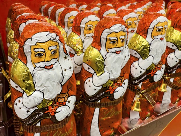 Display on the shelf of chocolate Santa Claus chocolate Santa Claus Santa Claus Santa Claus Santa Claus chocolate Santa Claus chocolate Santa Claus chocolate lice Santa Claus chocolate lice Santa Claus in color red of red staniol paper made of chocolate arranged like army of Santa Claus, Germany