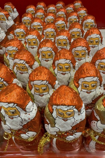 Display on the shelf of chocolate Santa Claus chocolate Santa Claus Santa Claus Santa Claus Santa Claus chocolate Santa Claus chocolate Santa Claus chocolate lice Santa Claus chocolate lice Santa Claus in color red of red staniol paper made of chocolate arranged like army of Santa Claus, Germany