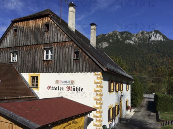 View of side view of Gasthof Ettaler Mühle in a historic two-storey baroque half-hipped roof dating from 1701 under listed building near Linderhof Castle, Ettal, Bavaria, Germany