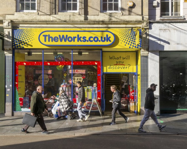 Shoppers passing The Works shop store in city centre, High Street, Exeter, Devon, England, UK