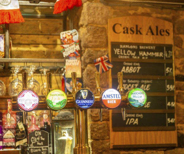 Keg beer taps and labels of different brands inside The Ship pub, Exeter, Devon, England, UK - cask ale menu in background
