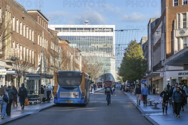 Buses and shoppers busy city centre street at Christmas, High Street, Exeter, Devon, England, UK