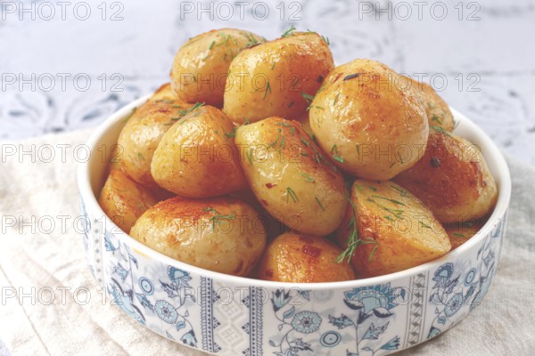 Baked new potatoes, with butter and dill, on a white plate, at home, no people