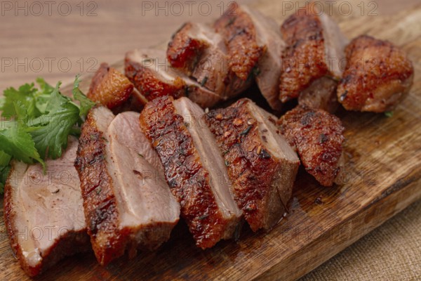 Roast duck breast, sliced, on a wooden chopping board, close-up, no people