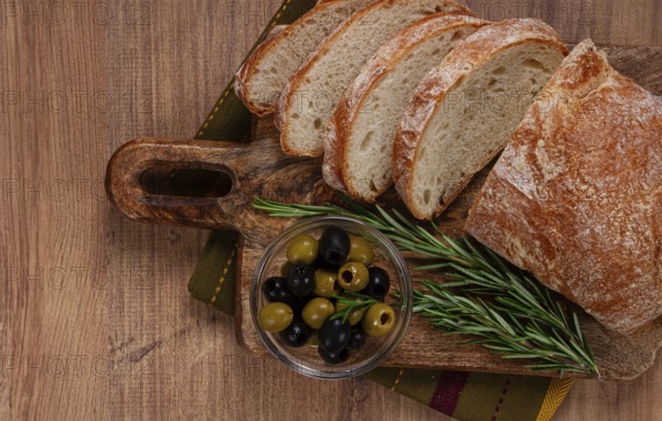 Sliced ciabatta, on a chopping board, with rosemary and olives, Italian bread, close-up, Italian cuisine, breakfast, no people