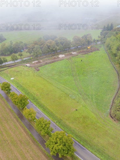 Aerial view of a green landscape with trees and a construction site along a road, Bau PV Freifaechenanlage, Weil der Stadt, Germany