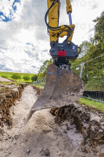 Close-up of an excavator digging a deep ditch, construction of a PV freeway plant, Weil der Stadt, Germany