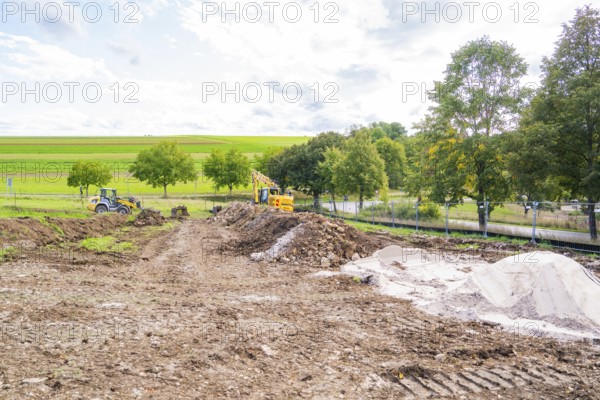 Extensive construction site with row of trees and machines in a rural landscape, construction of a PV open-air plant, Weil der Stadt, Germany