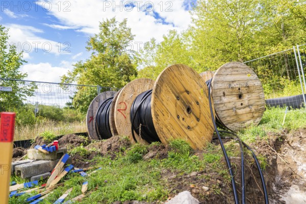 Several large cable drums with cables on a construction site in a green area, Bau PV Freifaechenanlage, Weil der Stadt, Germany