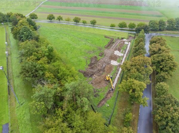 Aerial view of a construction site with excavator, surrounded by fields and trees, construction of a PV open-air system, Weil der Stadt, Germany
