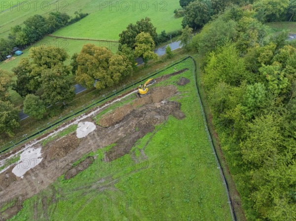 Aerial view of a construction site with excavator in a green field landscape, Bau PV Freifaechenanlage, Weil der Stadt, Germany