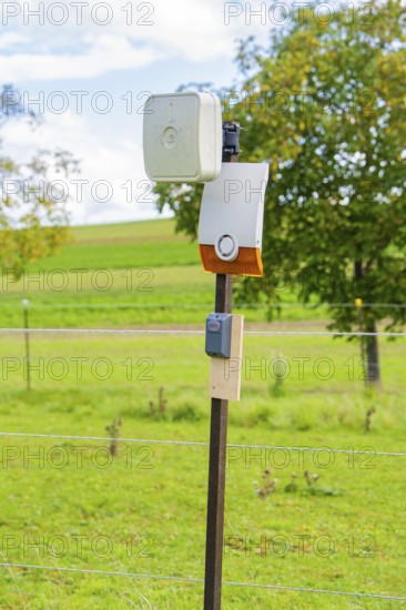 Camera mounted on a fence post in a rural landscape in front of a green field, Bau PV Freifaechenanlage, Weil der Stadt, Germany