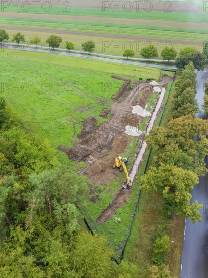 Aerial view of a construction site with excavator in a green landscape in autumn, construction of a PV open-air system, Weil der Stadt, Germany
