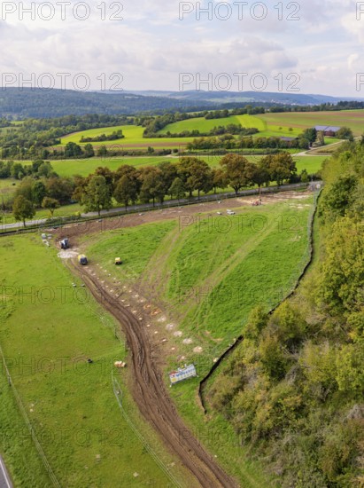 Extensive green landscape with trees, a path and rolling hills under cloudy sky, Bau PV Freifaechenanlage, Weil der Stadt, Germany