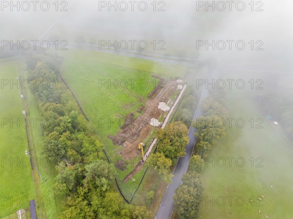 Fog-covered aerial view of a construction site with excavator in rural area, PV open-air plant construction, Weil der Stadt, Germany