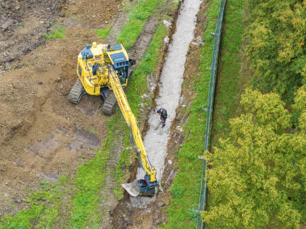 Excavator and construction worker at a ditch on a construction site, Bau PV Freifaechenanlage, Weil der Stadt, Germany