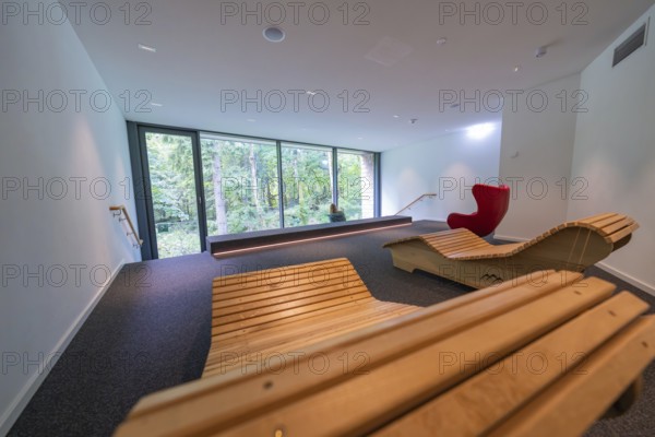 Modern room with wooden loungers and a wide view of a green forest through large glass windows, Ruhestein National Park Center, Black Forest, Baiersbronn, Germany