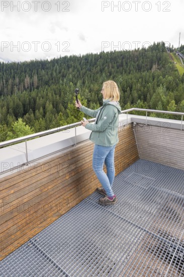 Person with selfie stick enjoying views of wooded hills from a vantage point, Ruhestein National Park Center, Black Forest, Baiersbronn, Germany