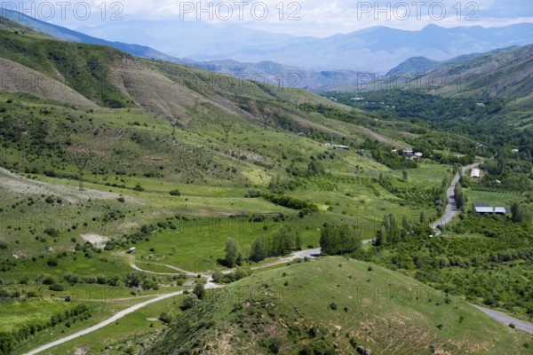 Green fields and rolling hills with roads leading through the area, under clear skies, countryside from the south towards Vardenyats Pass or Selim Pass, Vayots Dzor Province, Armenia