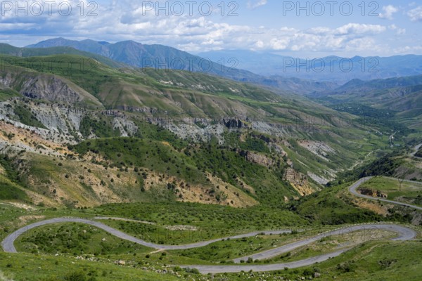 A winding road winds through the green mountains under a blue sky, view from Vardenyats Pass or Selim Pass, Vayots Dzor Province, Armenia