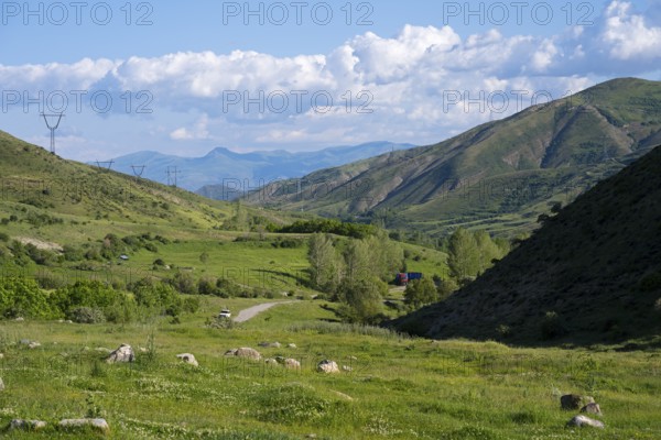 Valley with green landscape, power lines, surrounded by mountains and under a cloudy sky, landscape from south towards Vardenyats Pass or Selim Pass, Vayots Dzor Province, Armenia