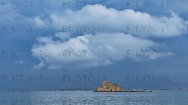 Bourtzi island fortress, a castle perched on a small island in blue water under a dramatic cloudy sky, Nauplion, Nafplion, Peloponnese, Greece