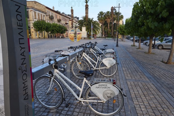 Old town of Nauplion, bicycles on a paved town square with historic buildings and palm trees, Nauplion, Nafplion, Peloponnese, Greece