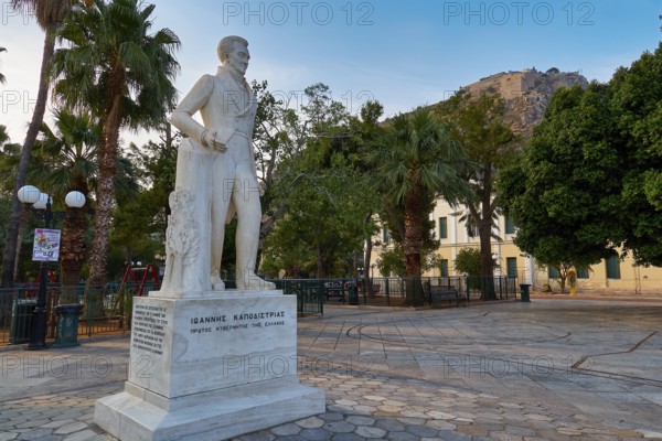 Old town of Nauplion, statue of Ioannis Kapodistrias, A statue stands in a square lined with palm trees in front of a historic building in the morning light, Nauplion, Nafplion, Peloponnese, Greece