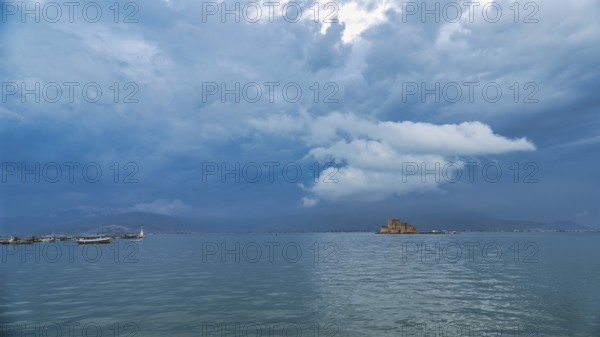 Bourtzi island fortress, an old castle stands on a small island in the calm sea under dramatic blue clouds, Nauplion, Nafplion, Peloponnese, Greece