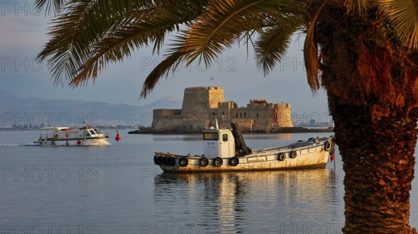 Bourtzi island fortress, port of Nauplion, boats near an old fortress on an island, framed by palm trees at sunset, Nauplion, Nafplion, Peloponnese, Greece