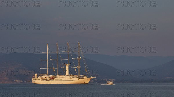 An illuminated sailing ship on calm water with mountains in the background at dusk, Nauplion, Nafplion, Peloponnese, Greece