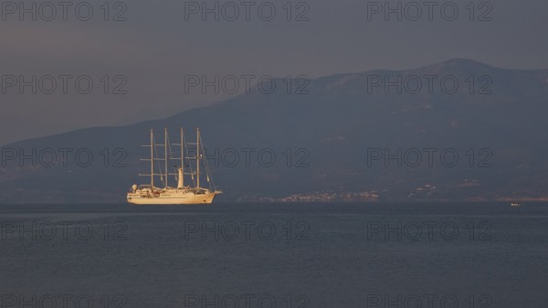 A large sailing ship sails in calm seas against a mountain backdrop at dusk, Nauplion, Nafplion, Peloponnese, Greece