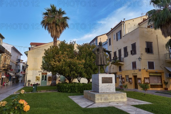 Old town of Nauplion, statue on a green area surrounded by buildings and palm trees under a clear sky, Nauplion, Nafplion, Peloponnese, Greece
