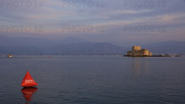 Bourtzi Island Fortress, A fortress in the sea at dusk with an orange buoy in calm water, Nauplion, Nafplion, Peloponnese, Greece
