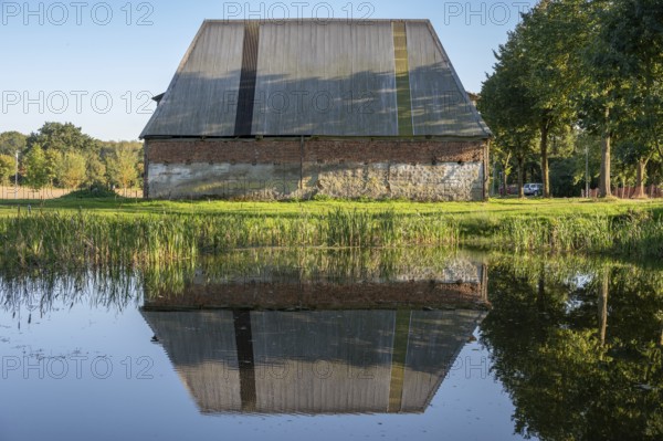 Old poultry house on an estate from 1923, reflected in the pond, Othenstorf, Mecklenburg-Western Pomerania, Germany