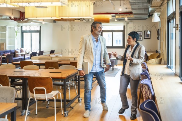 Diverse business professionals walking, talking, and discussing work in an open plan office, highlighting teamwork, innovation, and a dynamic corporate environment