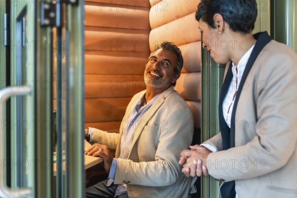 Business professionals having an engaging conversation, discussing work in a contemporary private soundproof booth within a co working space during a productive workday