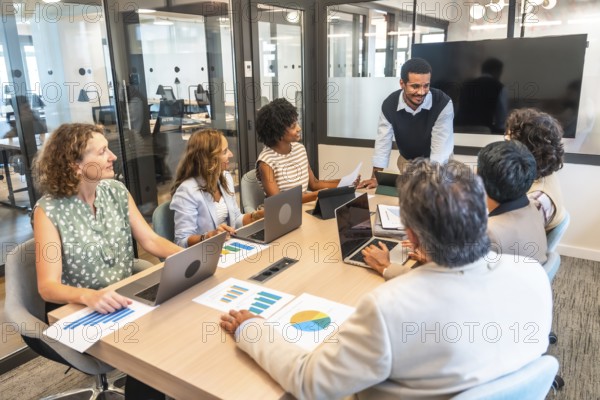 Diverse business professionals conducting a collaborative meeting in a modern office, analyzing data and discussing strategy, representing teamwork and corporate success