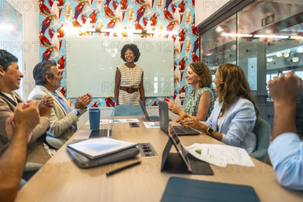 Diverse business colleagues showing appreciation for a successful presentation in a modern coworking office, celebrating collaboration and teamwork during a meeting