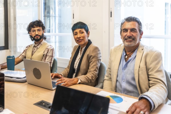 Diverse business colleagues working together around a table in a bright coworking office, smiling while planning a new business strategy and sharing ideas