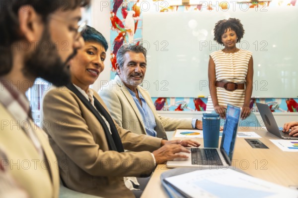 Diverse business colleagues holding a meeting or presentation, working and smiling in a colorful modern office space, discussing ideas and planning work
